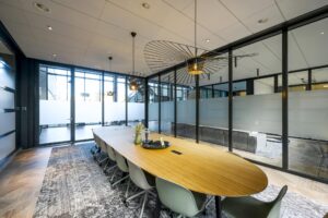 Moderne vergaderruimte aan de H.J.E. Wenckebachweg met lange houten tafel, glazen wanden en designverlichting.